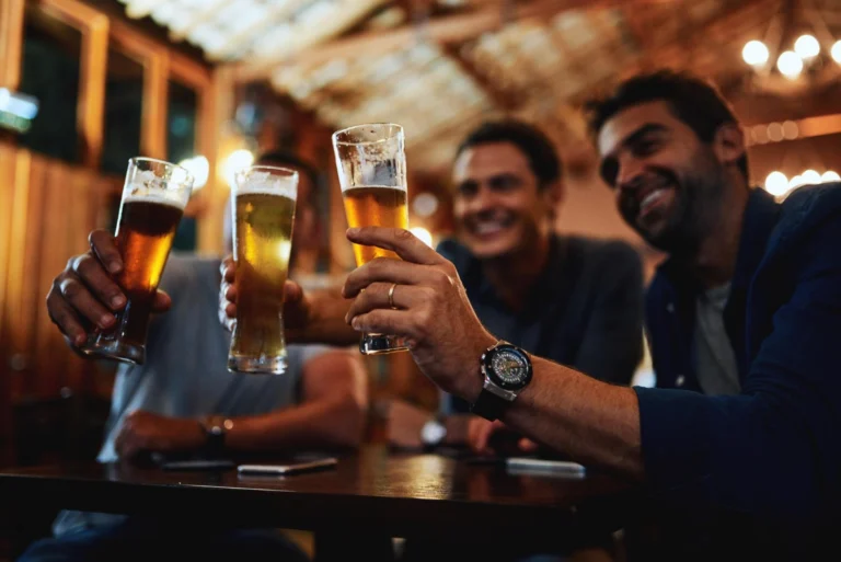 Homem com exxpressões felizes segurando taças de cerveja, fazendo um brinde